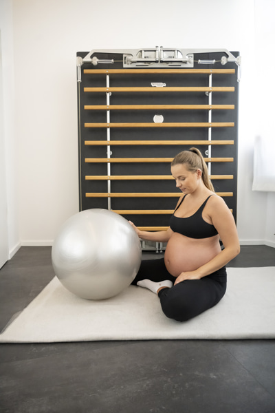 Schwangere Frau sitzt zur Rückbildungsgymnastik am Boden